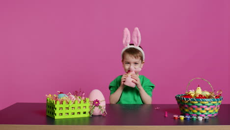 adorable little child playing with a stuffed rabbit and a pink egg at table