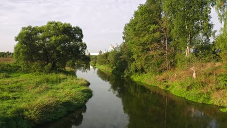 Aerial-View-Of-Landscape-With-River-Among-Glade-And-Woodland-On-Moody-Summer-Day