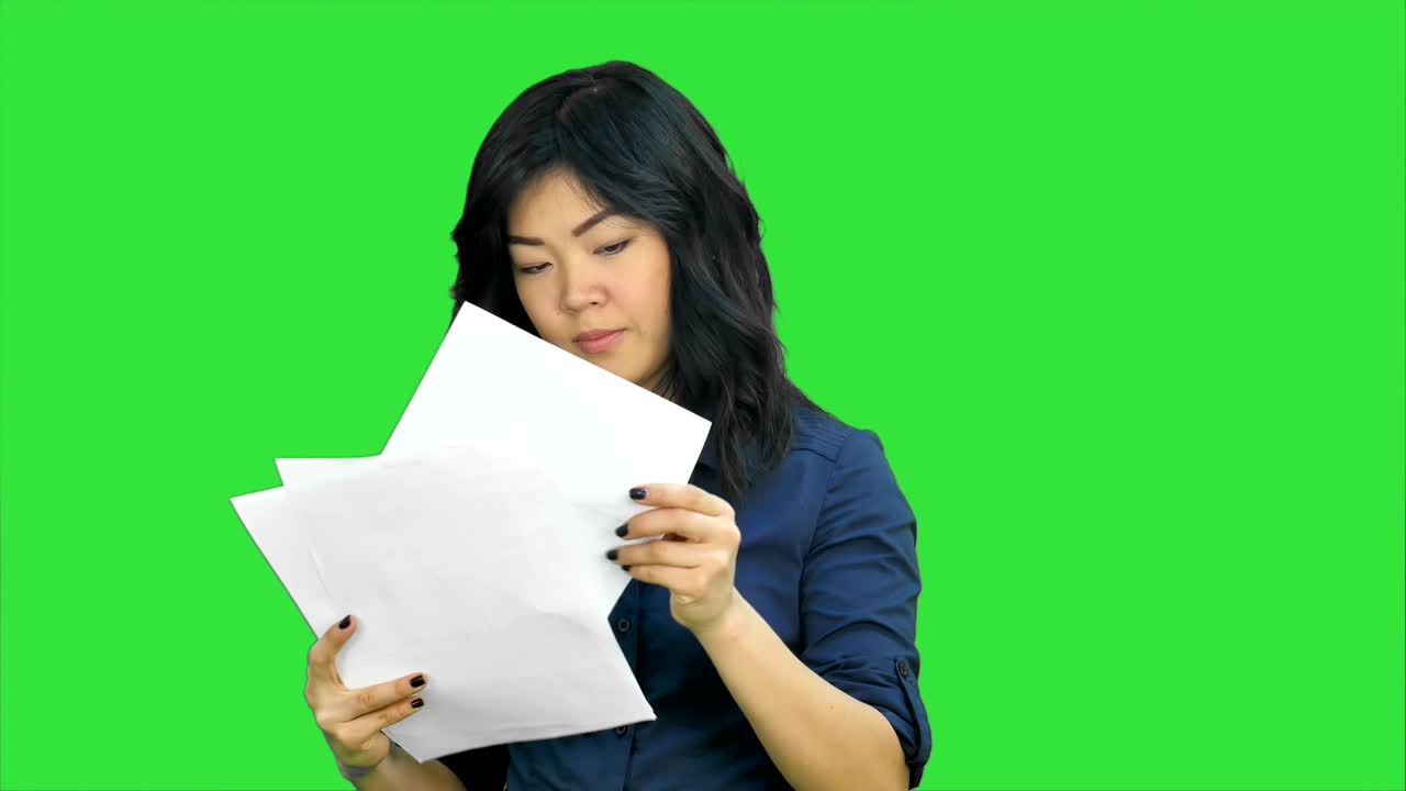Donna d'affari asiatica che guarda un documento nella sua mano su Green Screen, Chroma Key.