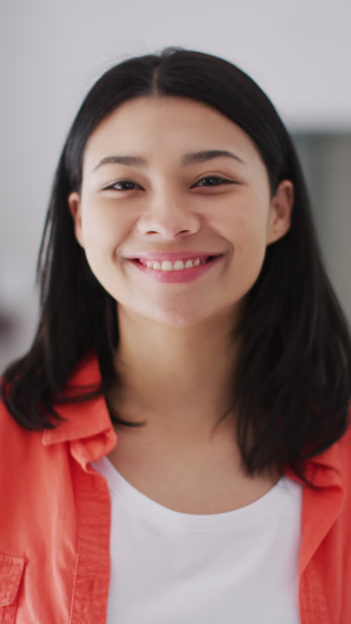 Vertical video of smiling biracial woman with dark hair looking at camera