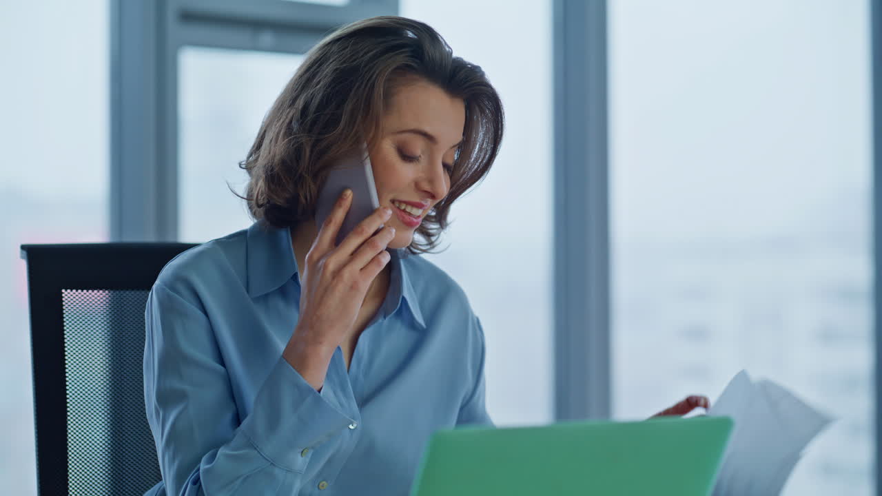 Fornøyd finansmann ringer med mobiltelefon og jobber med dokumenter på arbeidsplassen i nærbilde