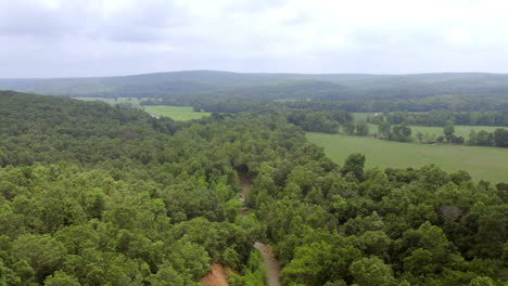 aerial landscape with panning over woods and pastures with rolling hills on the horizon in southern missouri