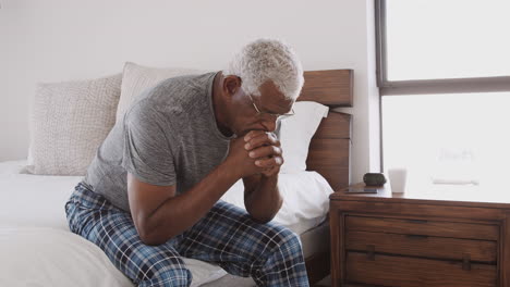 Depressed-Senior-Man-Looking-Unhappy-Sitting-On-Side-Of-Bed-At-Home