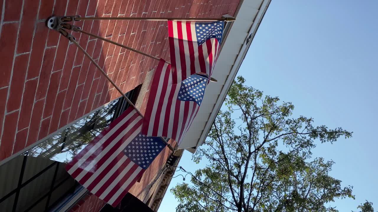 Three mini American flags posted on a brick wall in the summer in South Philly