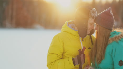 mírense con ojos amorosos mientras esquían en el bosque invernal. una pareja casada practica un estilo de vida saludable