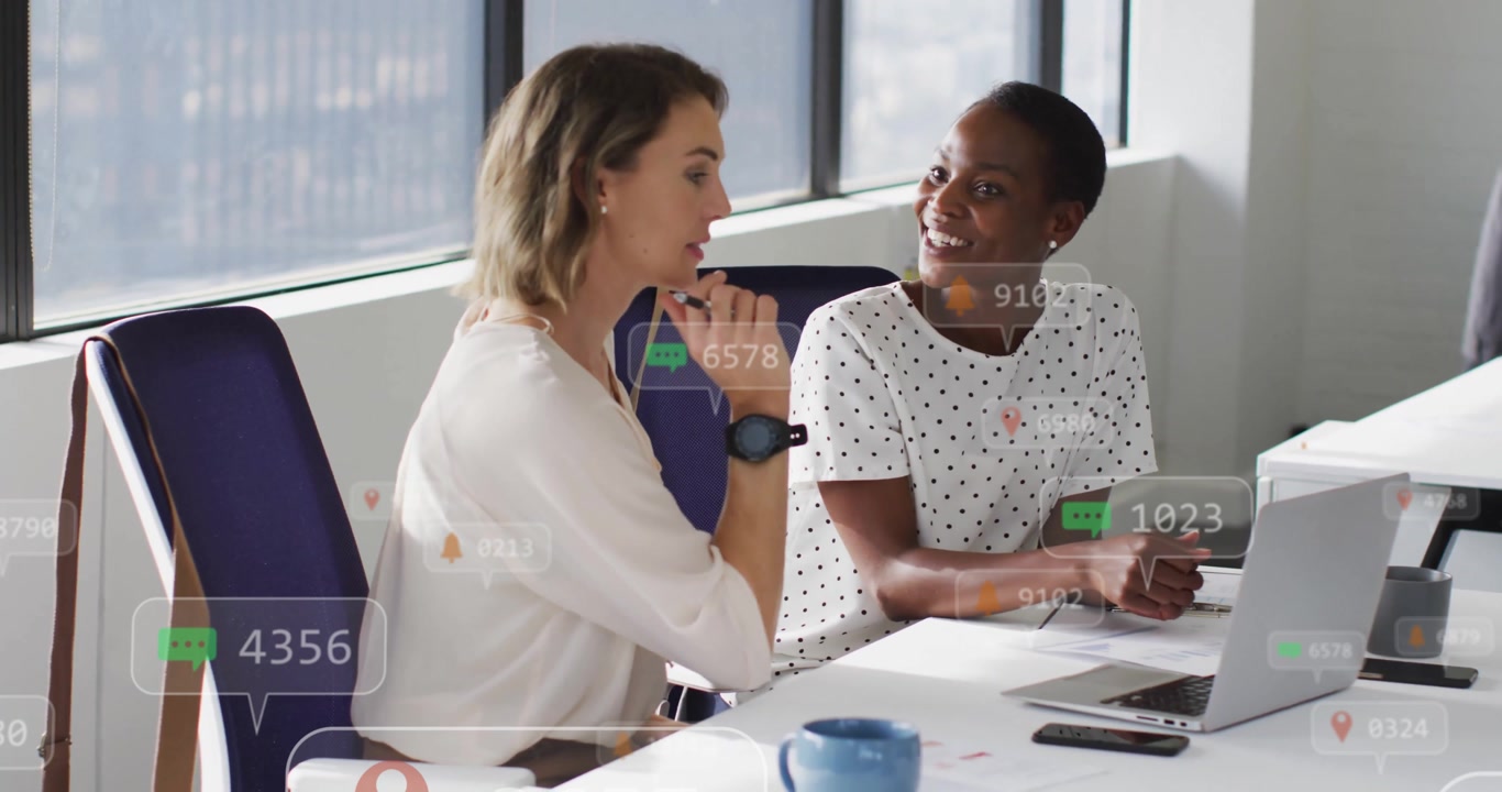 Women collaborating on marketing outlining plan revealing social media icons appearing over laptop
