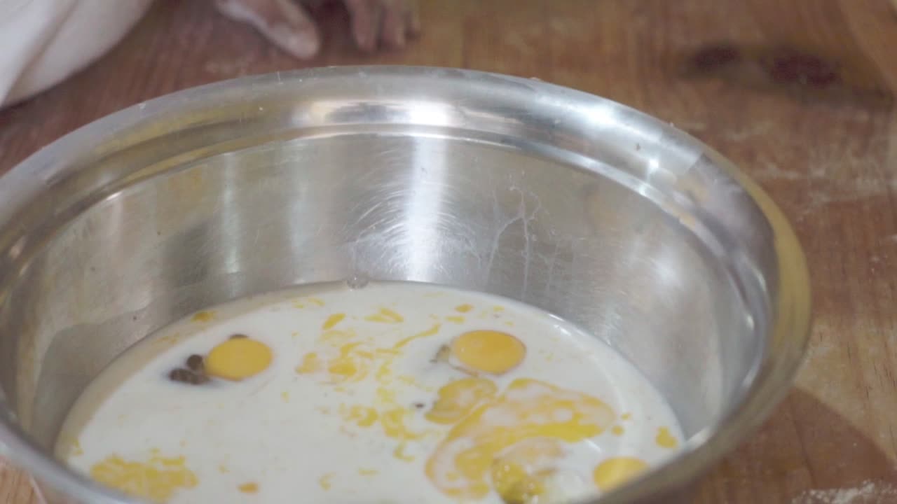 un cuenco con huevos, leche y otros ingredientes para hornear en una panadería, preparando una receta