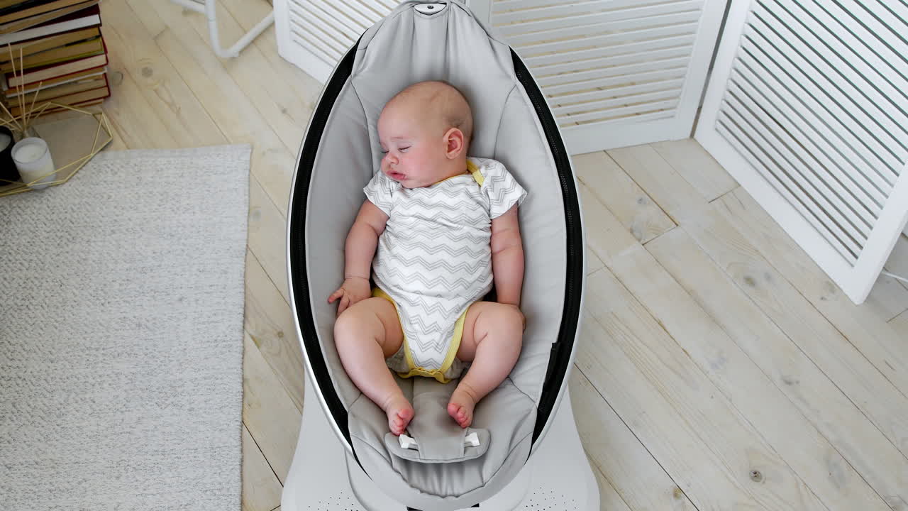 el bebé duerme en una silla mecedora para niños diseño de alta tecnología en el dormitorio blanco