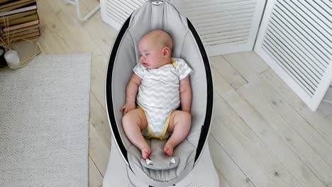 baby sleeps in a rocking chair for children high-tech design in white bedroom