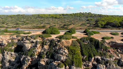 drone footage flying over the cliffs towards, and over, a road with cars driving on it