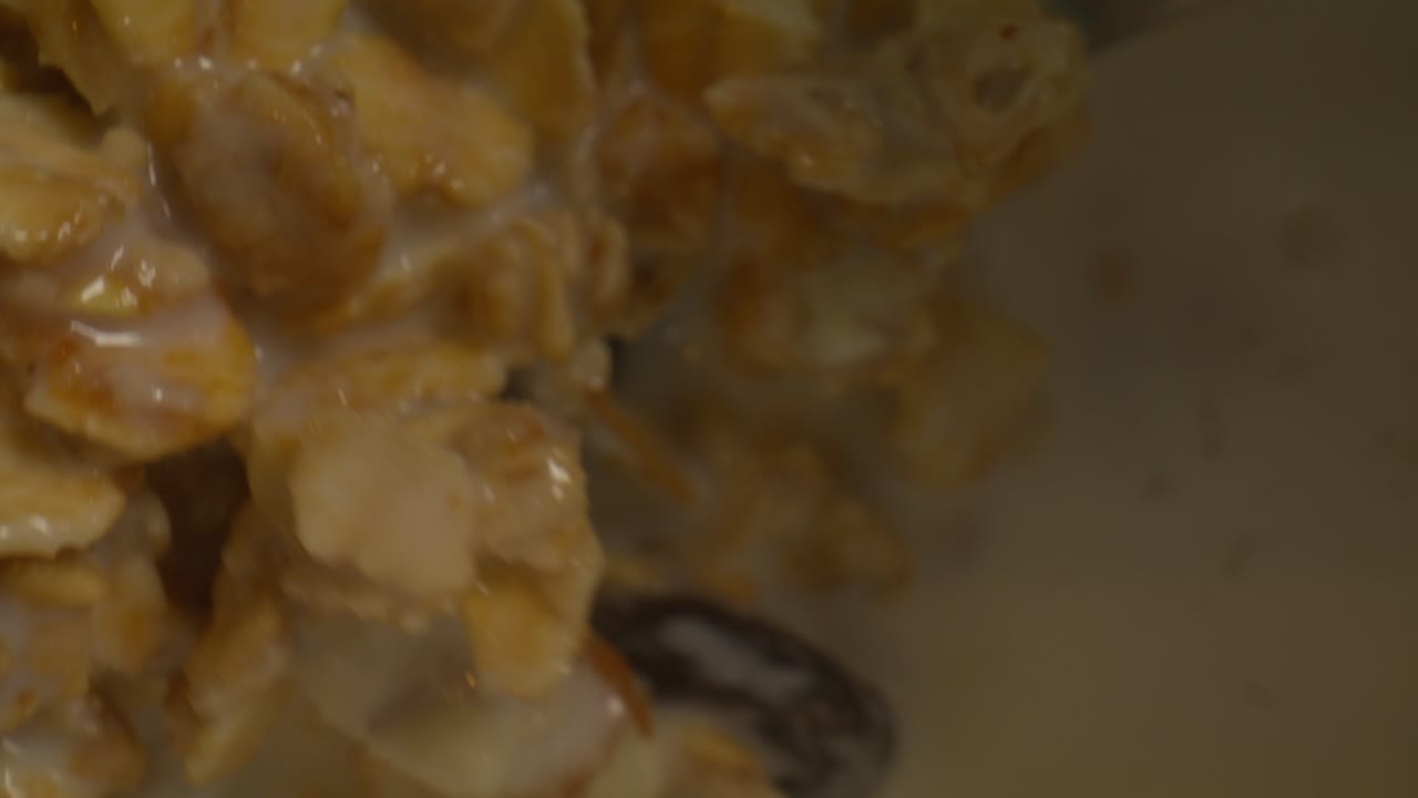 Macro di Granola con latte e cucchiaio che gira