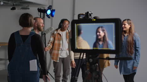 female production assistant uses clapperboard as actors shoot movie or video in studio with film crew and director 2