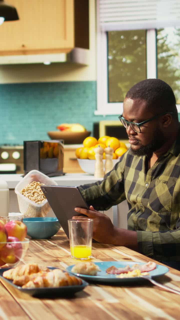 Vertical Video African american unfocused father paying attention to work on tablet