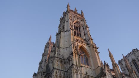 wide angle parallax looking up at the main tower on huge stone cathedral york minster on a clear sunrise