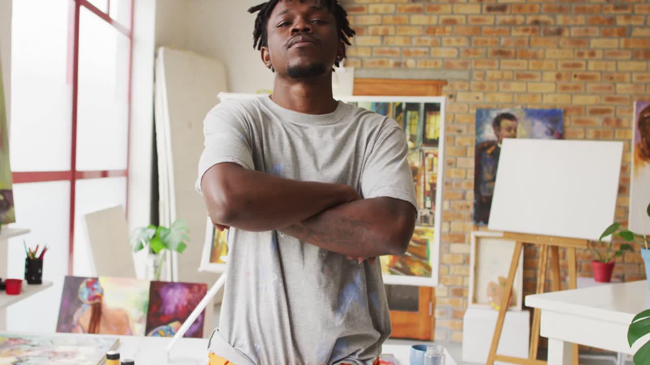 Retrato de artista afro-americano com os braços cruzados em estúdio de arte.