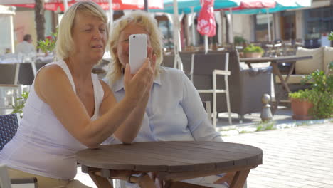 senior women friends taking selfie in street cafe