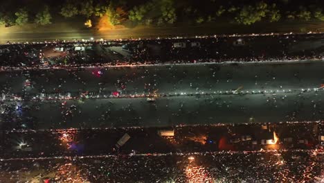 aerial birds eye view of people walking along road in karachi at night for pti party rally on 16 april 2022