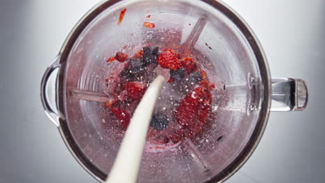 fresh milk pouring blender bowl with ripe berries in super slow motion close up.