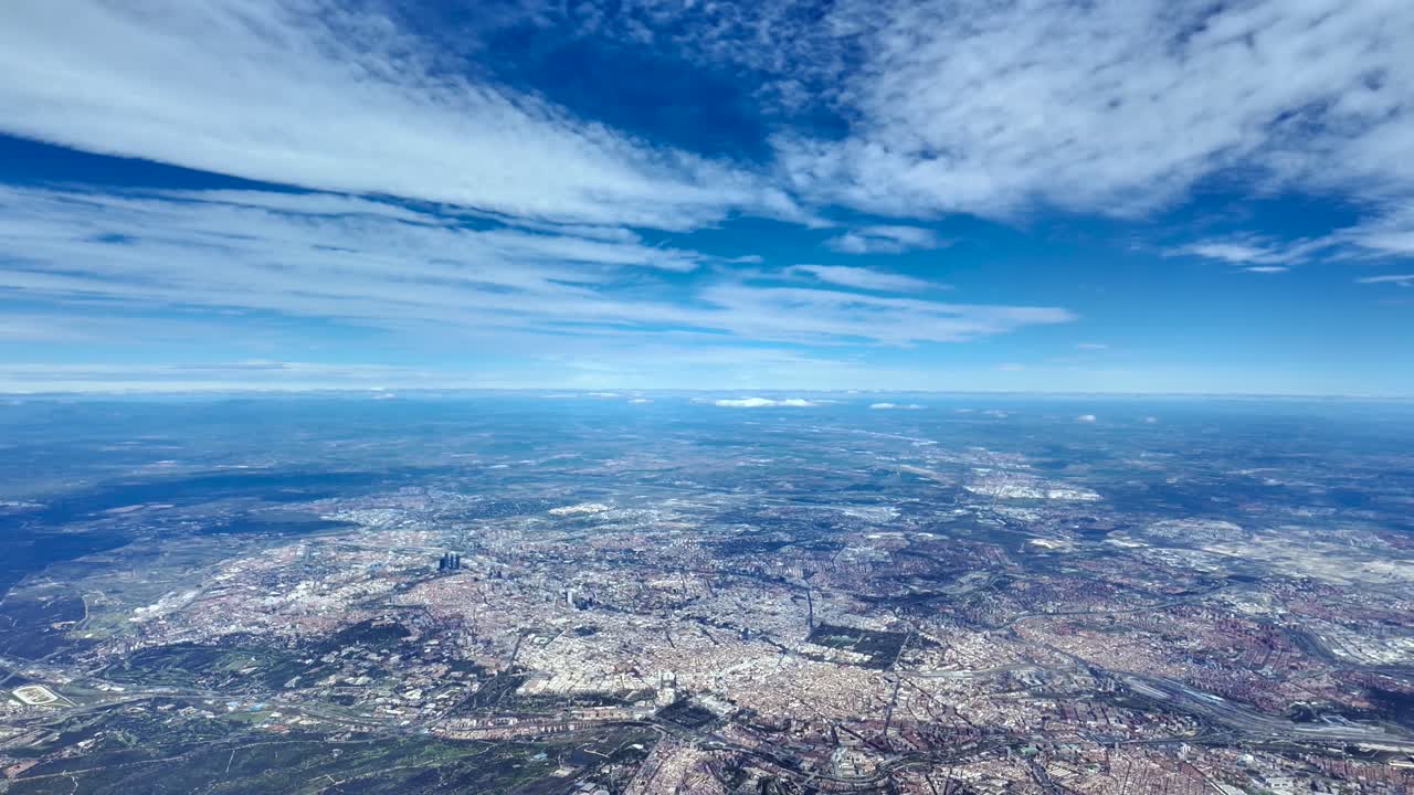 Pemandangan udara tinggi dari kokpit pesawat kota Madrid dan sekitarnya di bawah langit biru dengan sedikit awan
