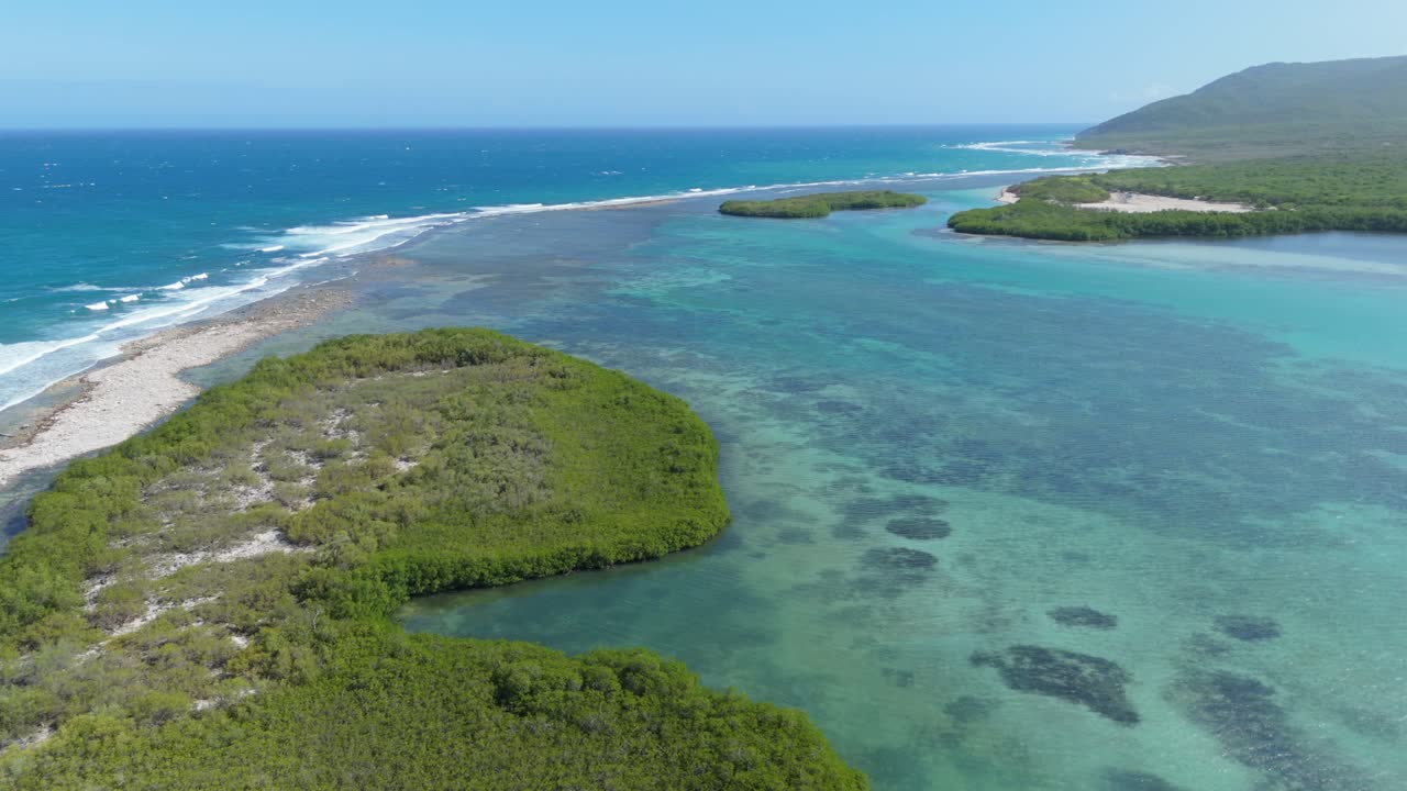Aerial establishing shot of turquoise water lagoon with Caribbean sea and tropical islands.Sunny day with blue sky and reaching waves. Wide shot. Sunny day in summer. Playa Caobita, Dominican Republic