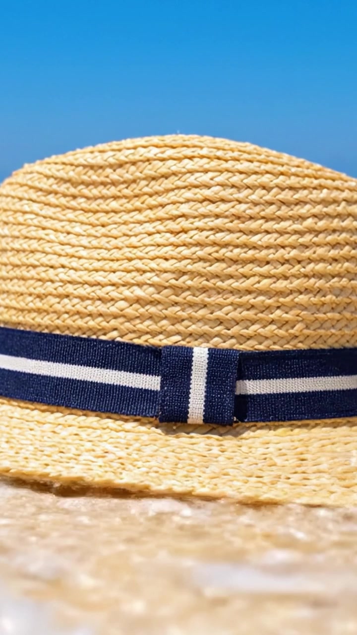 Zongekuste zomerse strohoed op zandstrand met helderblauwe lucht: perfect accessoire voor buitenavonturen en ontspanning onder de zon