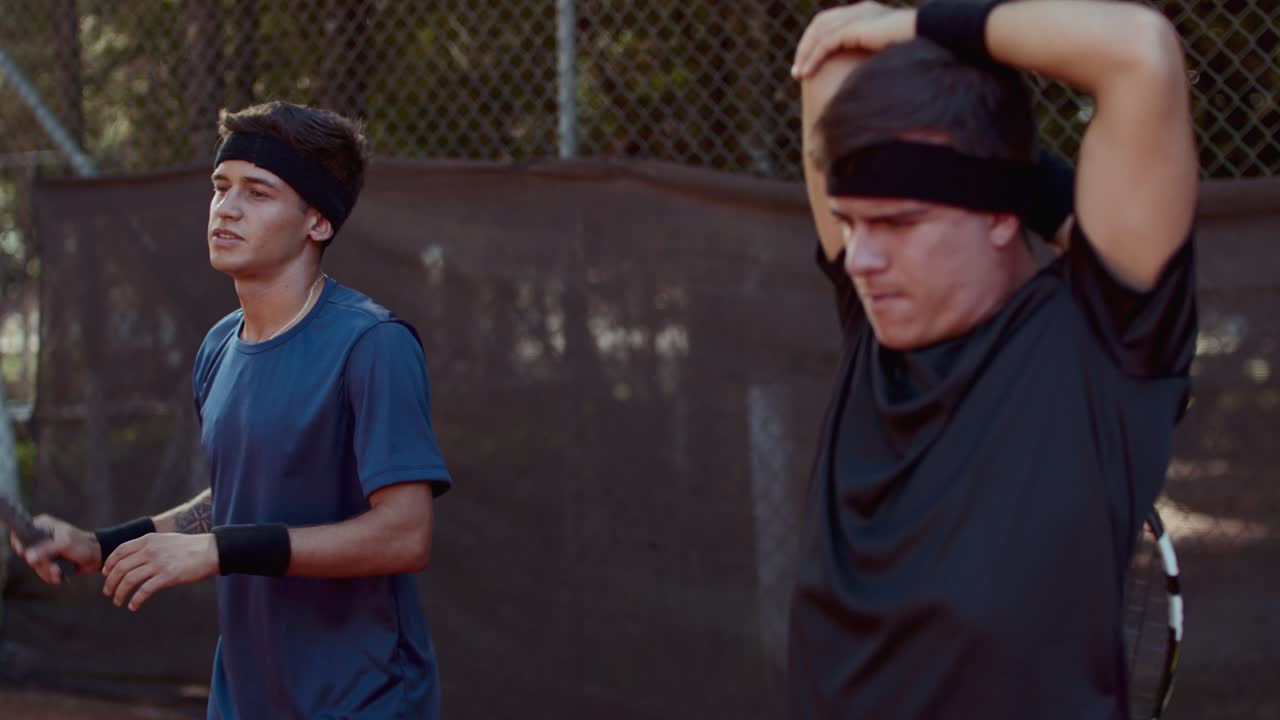 Two tennis players stretching and warming up on a court