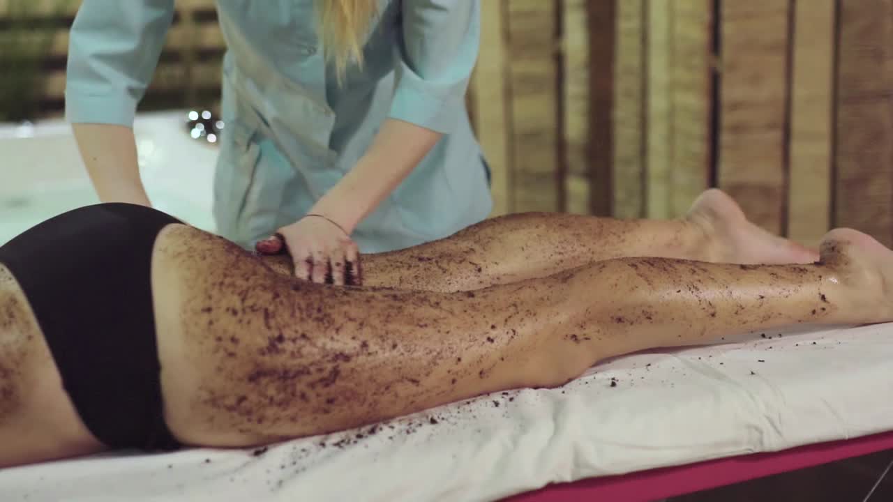 Woman receiving body scrub massage at a spa