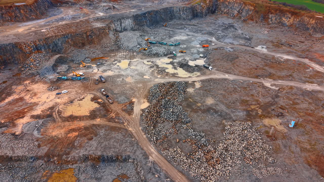Heavy machinery works at gravel site. Workers operate several machines at a gravel site during the day, moving materials in a large mining area