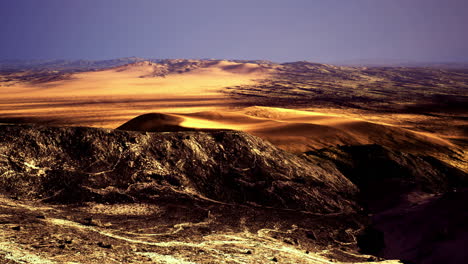 Vast golden landscape under twilight sky in arid region with rocky terrain