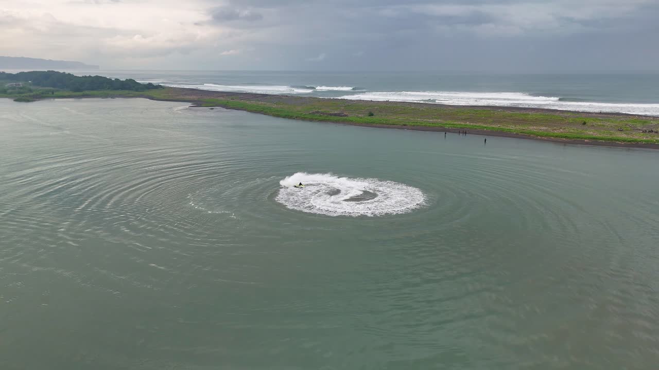 Drone view a jet ski running circles in the calm water surface beach.