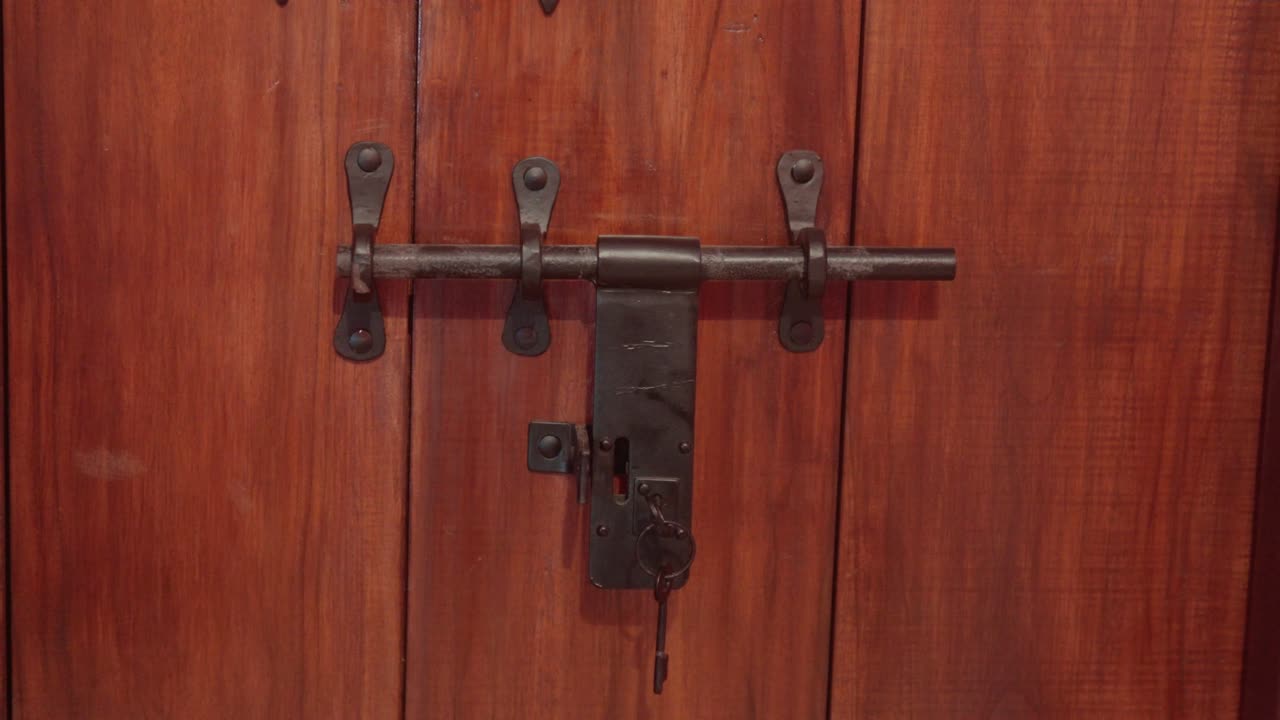 Rustic wooden door with an old metal lock and latch in close-up view