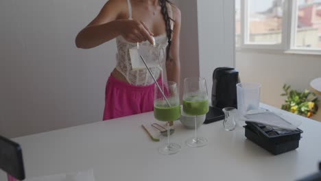 woman making green smoothie in kitchen