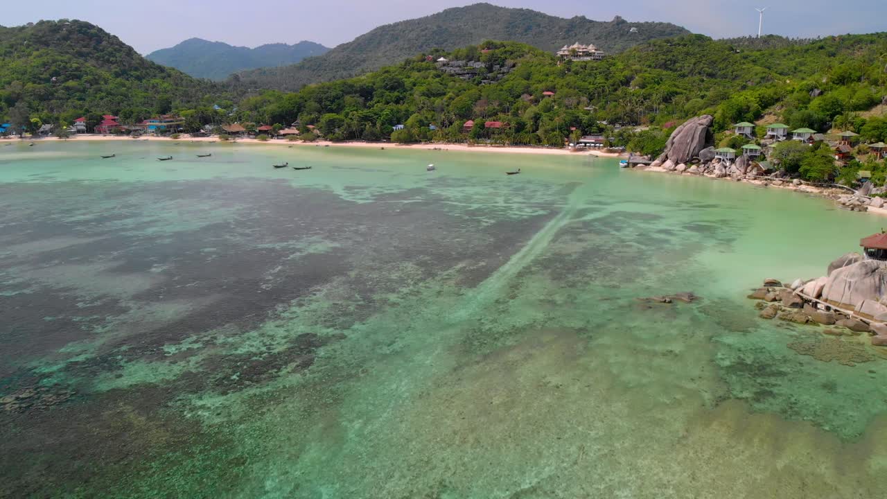 Aerial view of Koh Tao's emerald-colored beach, with mountains and forests at the shore