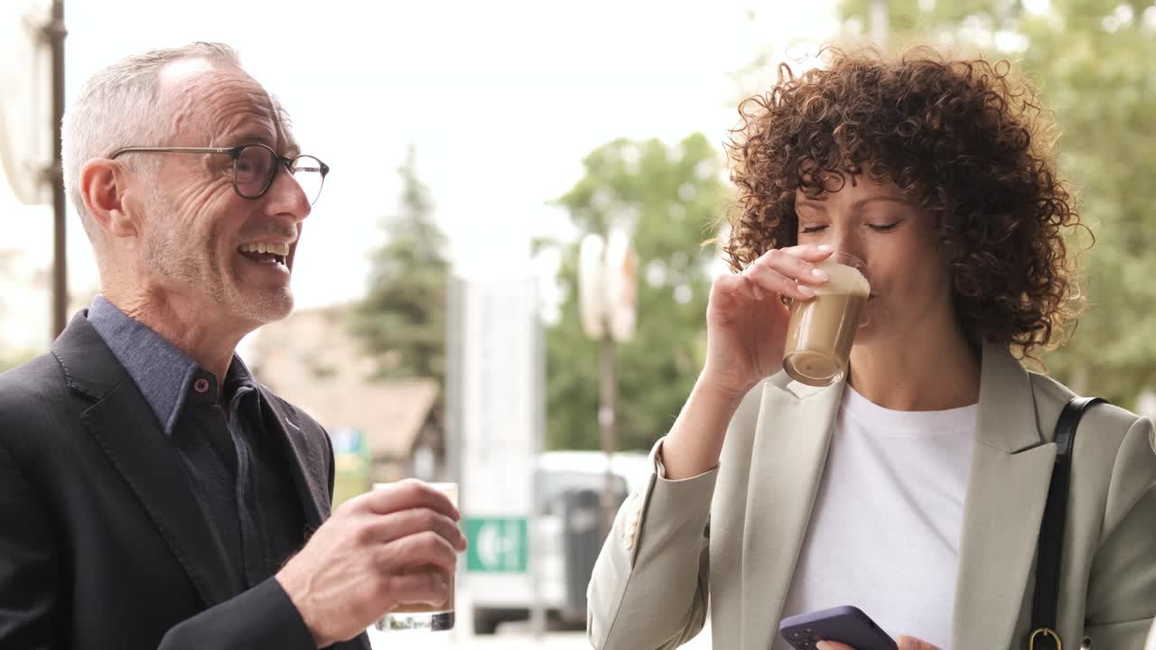 Cheerful business people using cellphone during coffee break