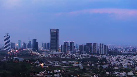 drone trucking pan across blue hour puebla city skyline with traffic driving below