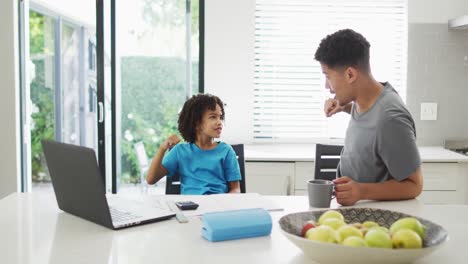 Hombre-Birracial-Feliz-Y-Su-Hijo-Haciendo-La-Tarea-Juntos,-Chocando-Puños