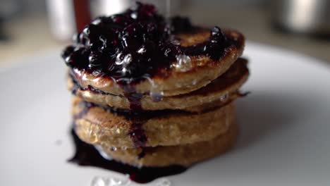 glazing four stacked pancakes and blueberry sauce with transparent syrup