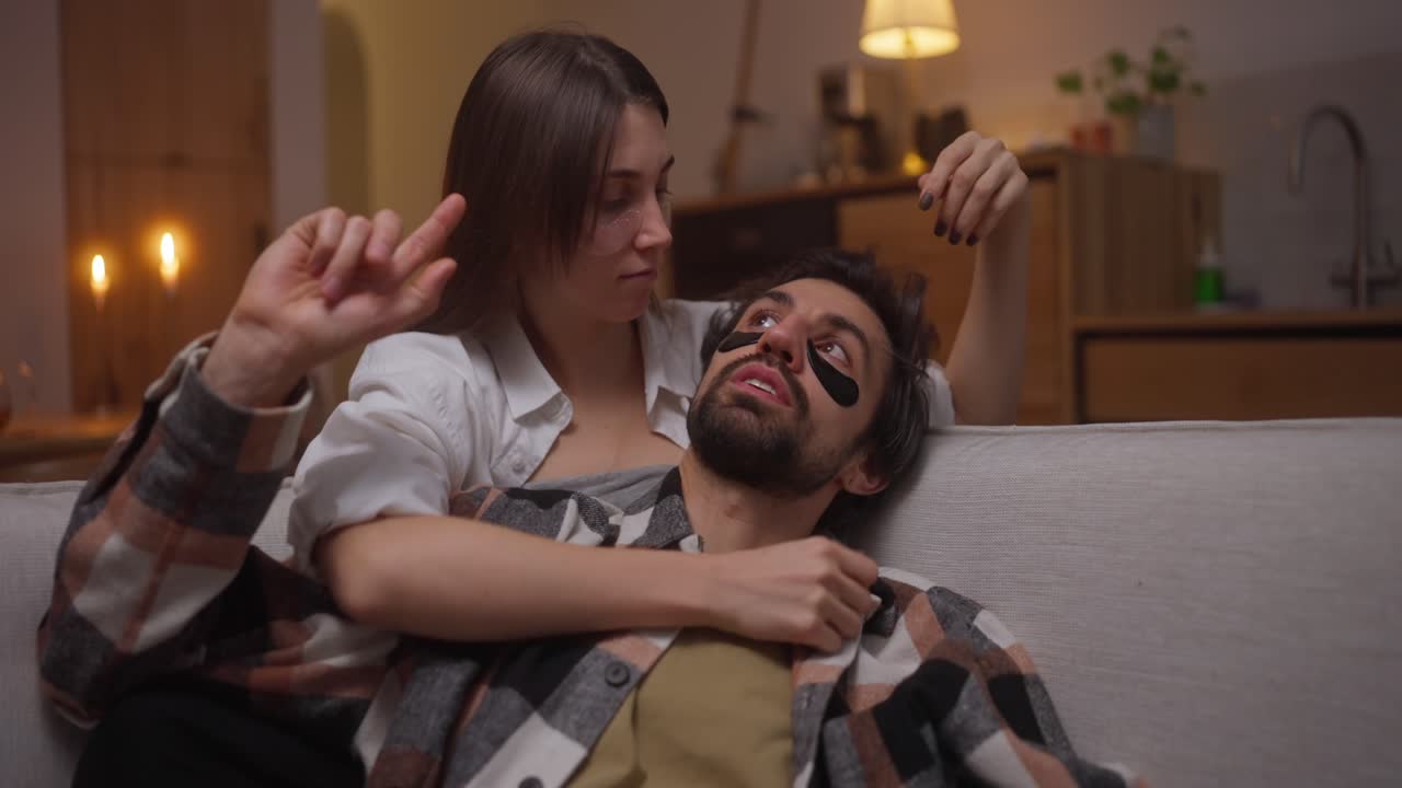 커플이 얼굴 마스크를 착용하고 집에서 휴식을 취하고 있습니다.