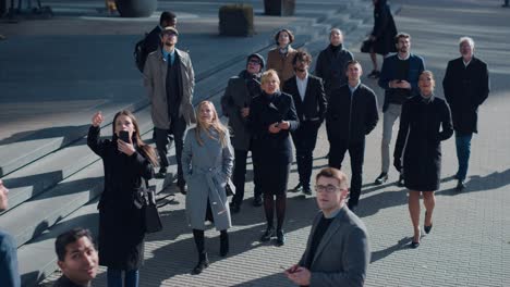 multicultural diverse office managers and business people suddenly stop on the street and look up. unbelievable, fantastic or tragic event happening live. crowd takes out smartphones and record video.