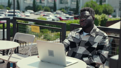 hombre trabajando en una computadora portátil en un café al aire libre