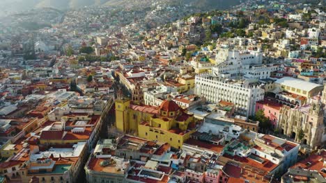 drone circles above guanajuato city center with mountain landscape in background