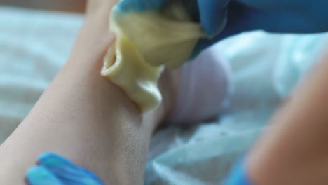 close-up in the beauty salon master in gloves doing the procedure to remove the hair on the legs with a sugar mixture