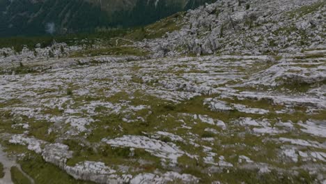 Aerial-tilt-up-shot-showing-moss-on-rocky-mountains-and-beautiful-mountain-range-in-background---Italian-Dolomites-during-sunny-day