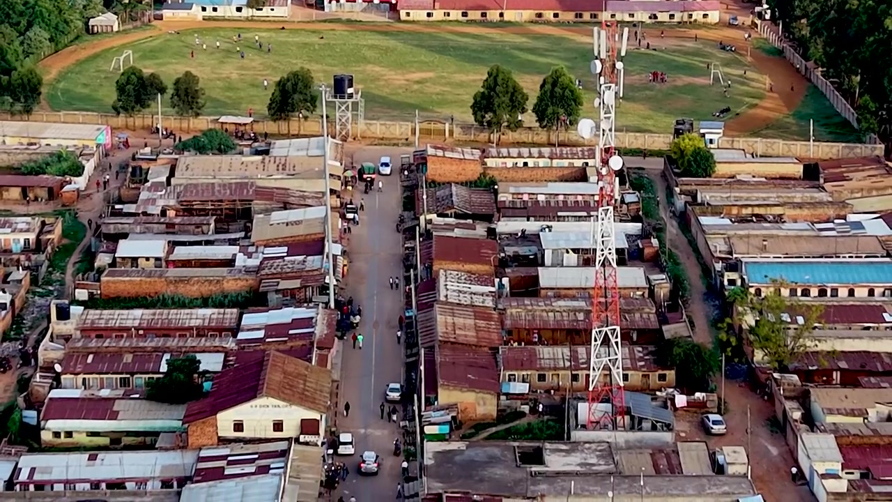 Drone che si allontana dal campo verso le povere baraccopoli del Kenya, campo da calcio della Coppa del Mondo, bambini poveri che giocano a calcio
