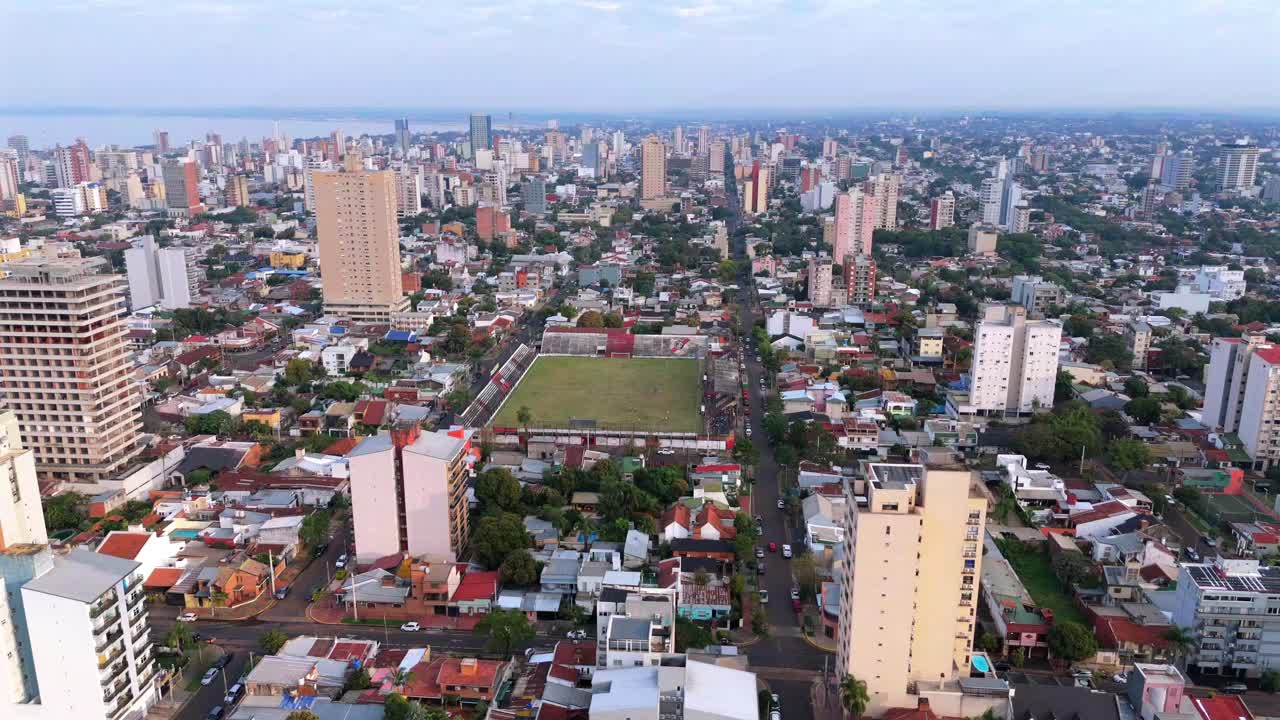 Filmato aereo con drone ad alta quota sopra il Club Deportivo Guarani Antonio Franco e la vasta città di Posadas, in Argentina, che si estende fino all'orizzonte durante il pomeriggio