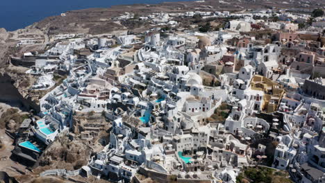 Vista-Aérea-De-Oia,-El-Pueblo-Más-Hermoso-De-La-Isla-De-Santorini-En-Grecia-Durante-El-Verano---Disparo-De-Drones