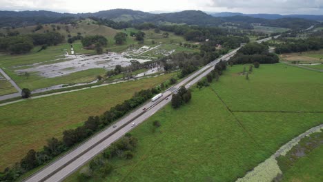 Vehículos-Circulando-Por-La-Autopista-Del-Pacífico-A-Través-De-Exuberantes-Campos-En-Tanglewood,-Nueva-Gales-Del-Sur,-Australia