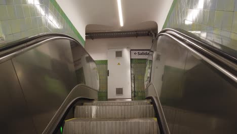 automatic silver staircase going up ascending inside underground vintage station with green tiles