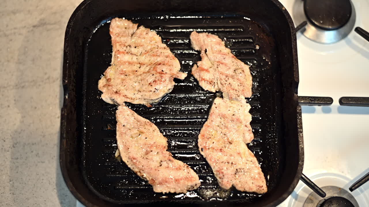 Tender chicken fillets sizzle on a hot cast iron pan in a warm kitchen. Seasoned perfectly for a delicious meal, they cook evenly while releasing savory aromas