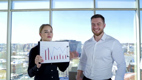 successful business workers shows new project. beautiful woman and handsome businessman talking on camera on the city view background through window.